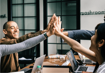 team high 5-ing at a desk